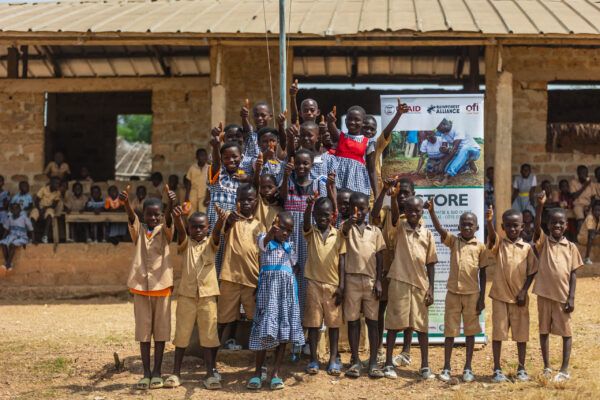 Group of smiling kids in Ghana and Côte d’Ivoire giving a thumbs-up.