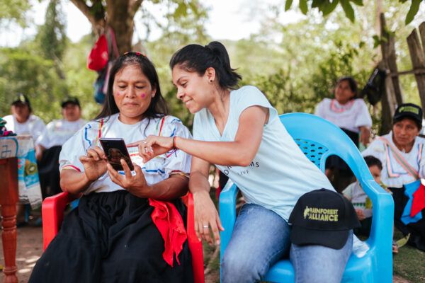 Two women in San Martín, Peru, smiling as they look at a phone together.